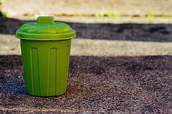 Green Miniature Trash Can on Asphalt Surface