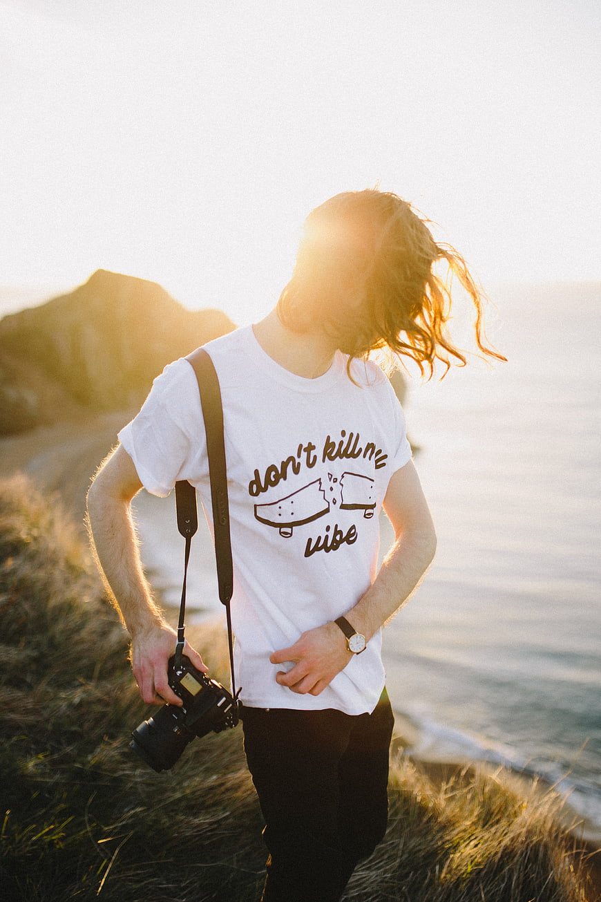 Young Photographer with Camera on Coastal Cliff at Sunset