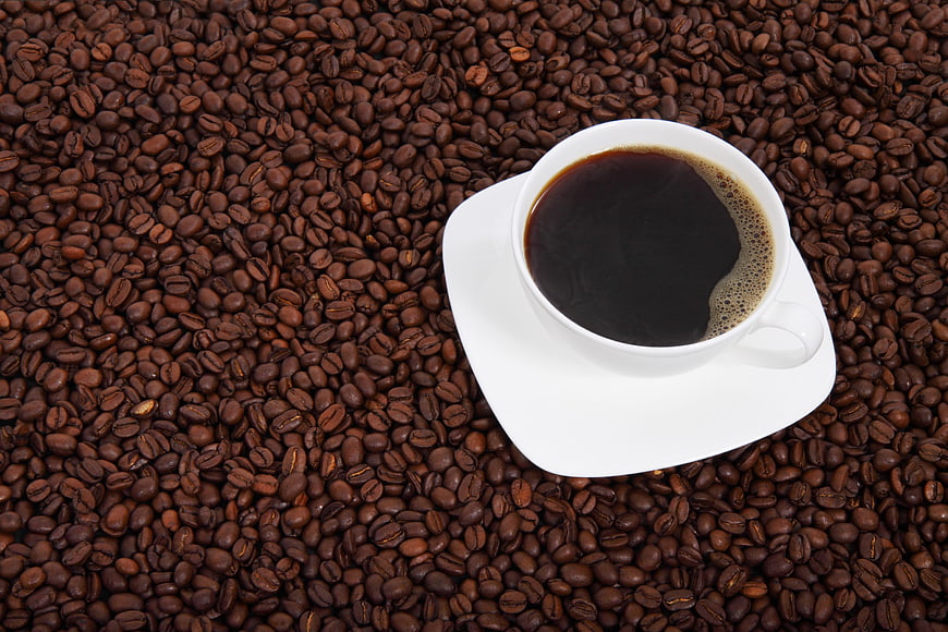 White Cup of Black Coffee on Bed of Roasted Coffee Beans