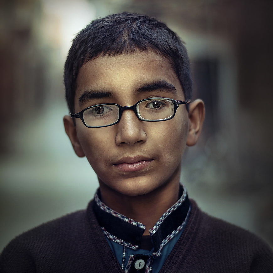 Portrait of a young boy with glasses looking at camera