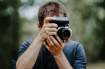 Man Holding Camera Outdoors in Forest