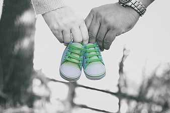 Parents holding colorful baby shoes against blurred background