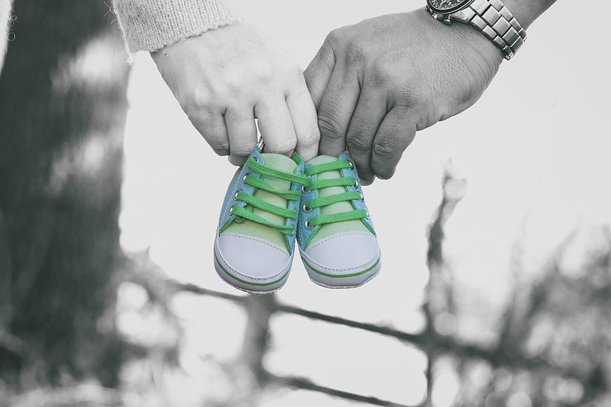 Parents holding colorful baby shoes against blurred background