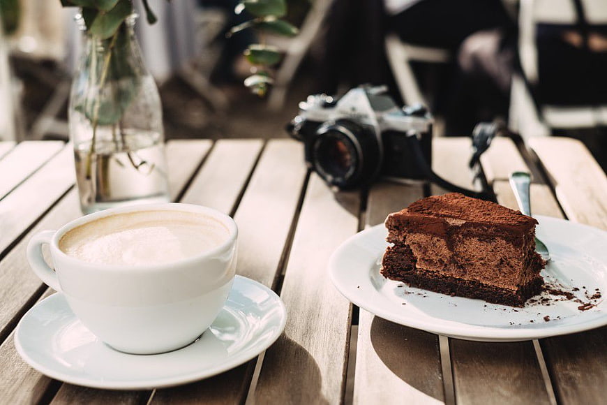 Cappuccino and Chocolate Cake with Vintage Camera on Wooden Table