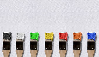 Row of Paint Brushes with Colorful Paint on White Wall