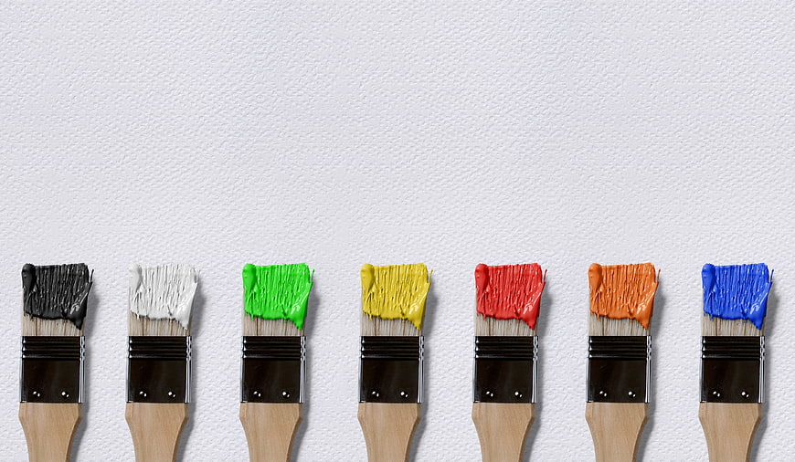 Row of Paint Brushes with Colorful Paint on White Wall