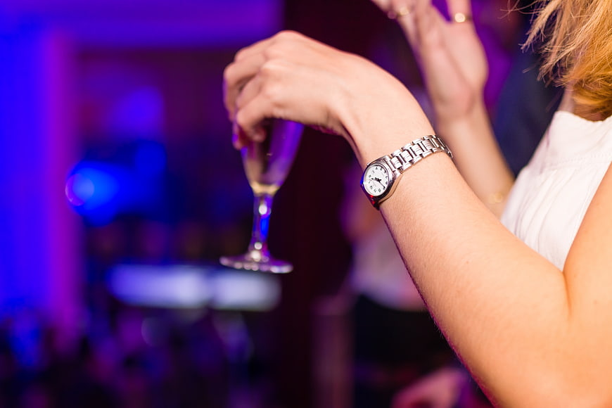 Woman holding champagne glass at nightclub with wristwatch