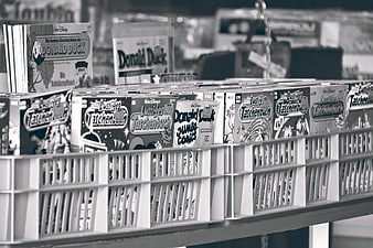 Black and white photo of used Disney comic books in a plastic crate