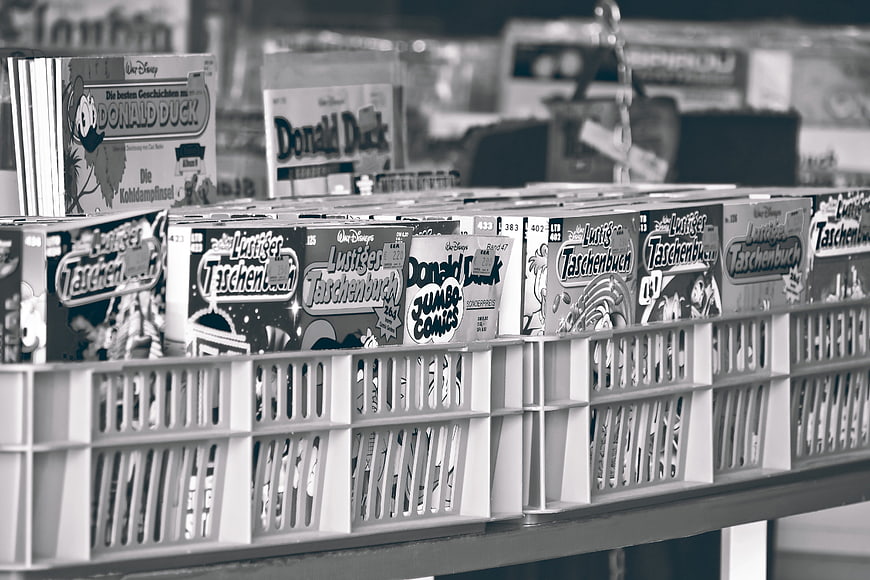 Black and white photo of used Disney comic books in a plastic crate