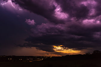 Dramatic purple lightning storm over sunset landscape