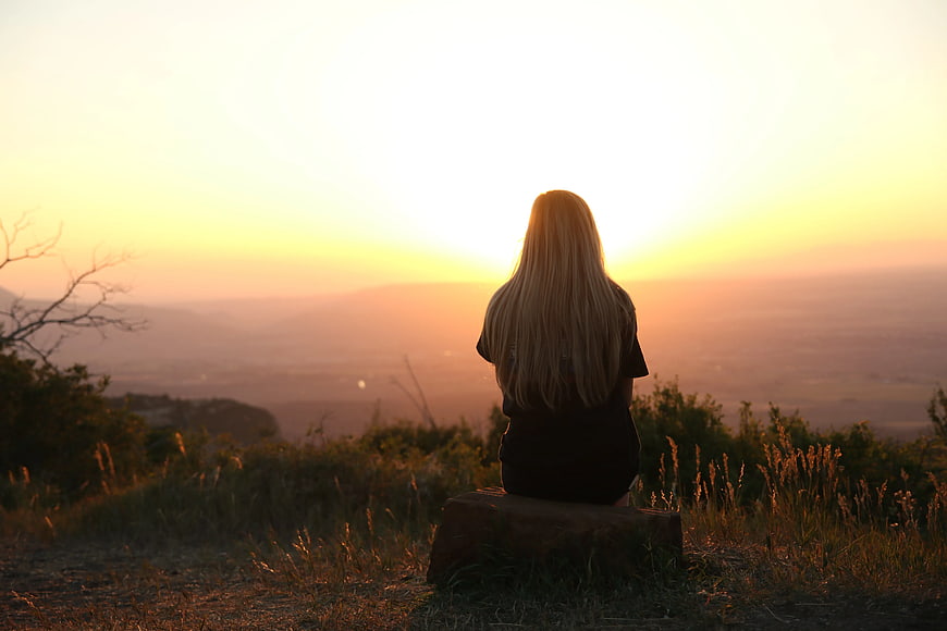 Woman Watching Sunset Over Hazy Mountain Valley