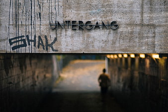 Man walking away in concrete tunnel with Untergang sign