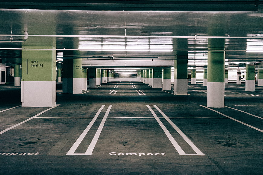 Empty underground parking garage with green and white pillars