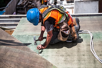 Construction worker hammering roof with safety gear