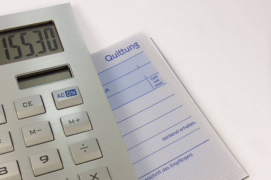 Silver Calculator and German Receipt Booklet on White Background