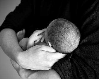 Black and white photo of newborn baby sleeping in arms