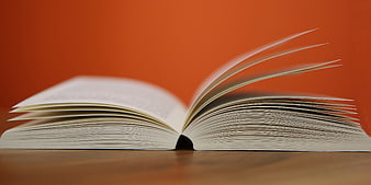 Open Book with Pages Turning on Orange Background