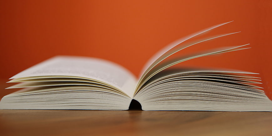 Open Book with Pages Turning on Orange Background