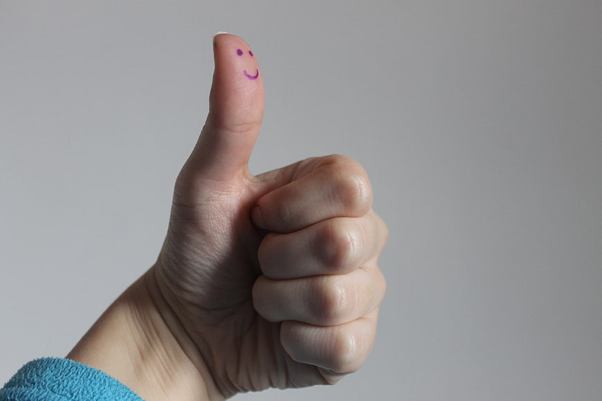 Hand Thumbs Up Gesture with Smiley Face on Thumb