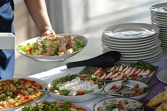 Catering staff serving fresh salad buffet with pizza and appetizers