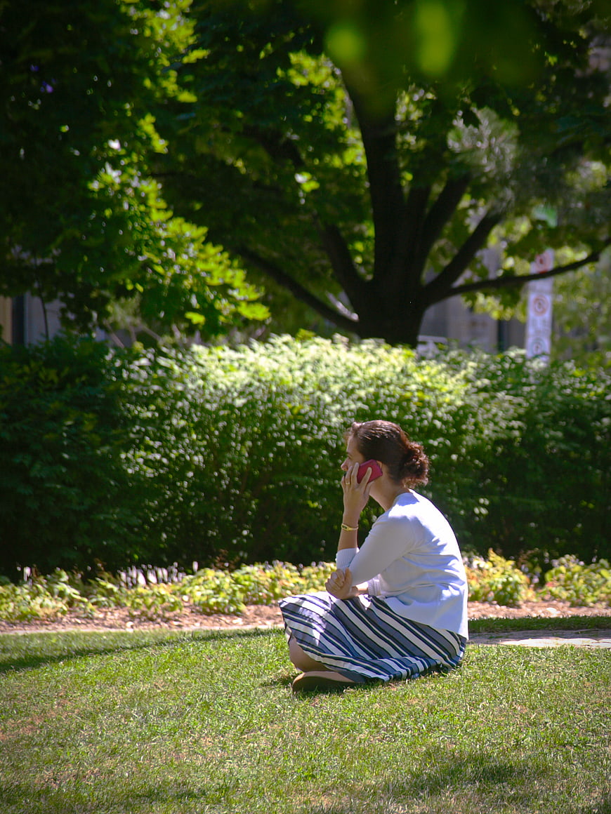 Woman Sitting on Grass Talking on Smartphone in Park