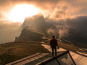 Hiker on Glass Platform Overlooking Dramatic Mountain Sunset