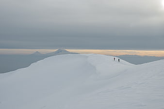Hikers on Snowy Mountain Ridge at Sunset