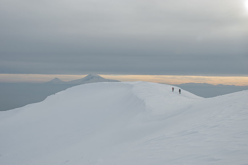 Hikers on Snowy Mountain Ridge at Sunset