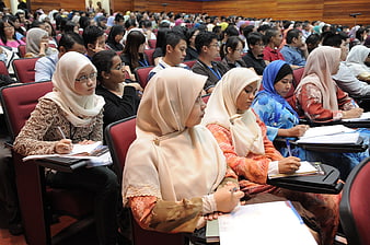Diverse students taking notes in a crowded university lecture hall