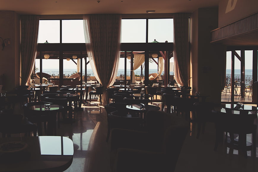 Sunlit restaurant interior with ocean view through large windows