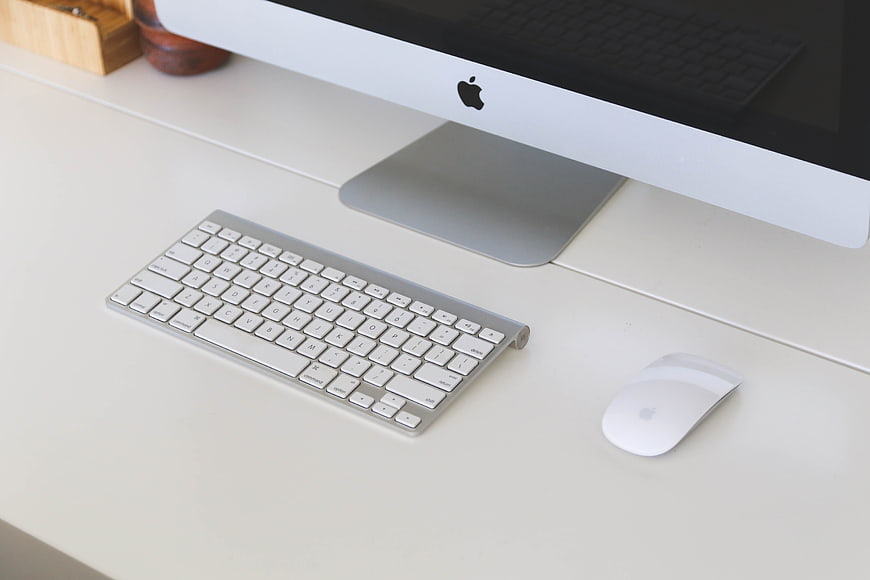 Minimalist white desk with Apple iMac, keyboard, and mouse