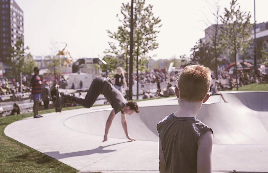 Young boy watching breakdancer perform at outdoor skate park