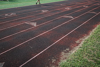 Red Running Track Lanes with Grass and Runner Legs