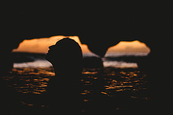 Silhouette of woman swimming in ocean at sunset