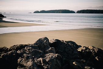 Serene Beach Landscape with Foreground Rocks and Distant Islands