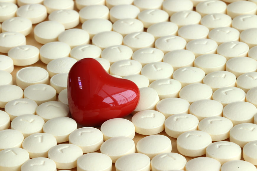Red Heart Shaped Pill Among White Tablets