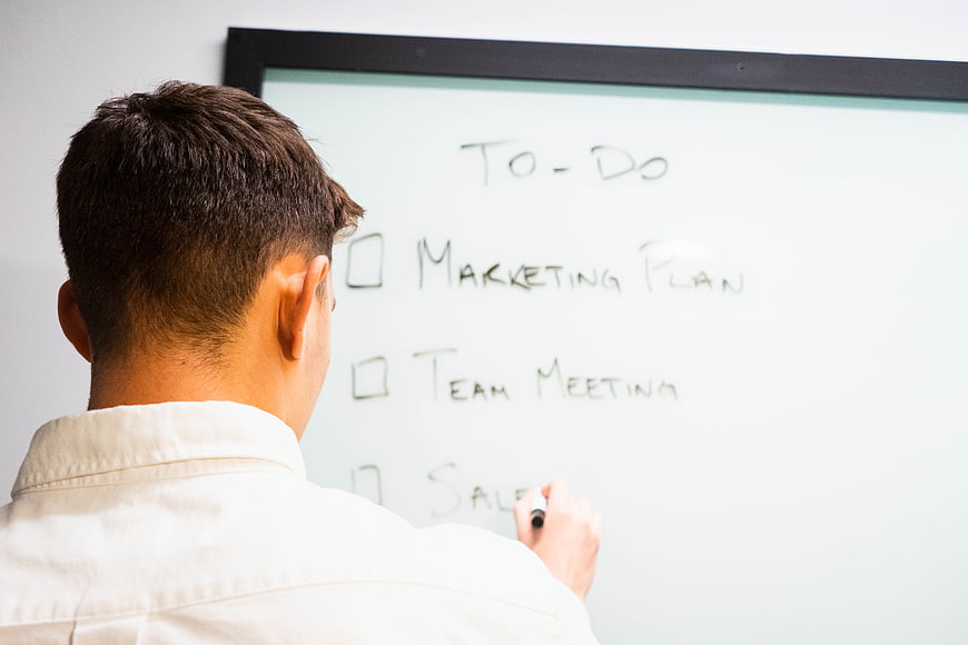 Man Writing To-Do List on Whiteboard in Office