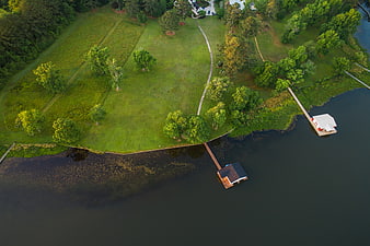 Aerial view of lakeside property with docks and green lawn