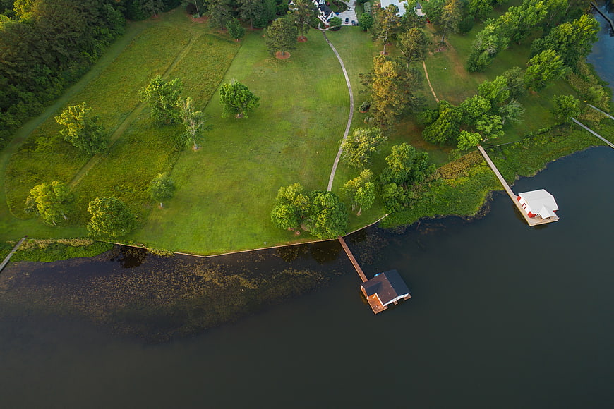 Aerial view of lakeside property with docks and green lawn