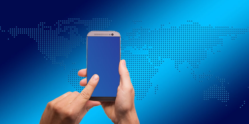 Hand holding smartphone with world map background