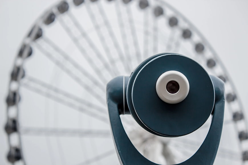 Blue Coin-Operated Binoculars with Blurred Ferris Wheel Background
