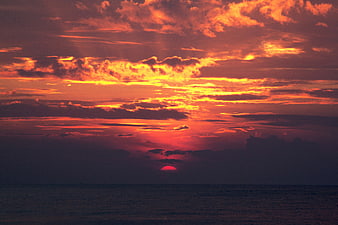Dramatic Fiery Sunset Over Ocean with Dark Clouds