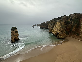 Dramatic coastal cliffs and sea stacks on a sandy beach in Algarve, Portugal