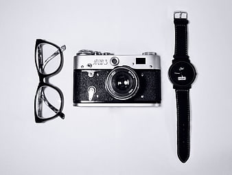 Vintage camera, glasses, and watch flat lay on white background