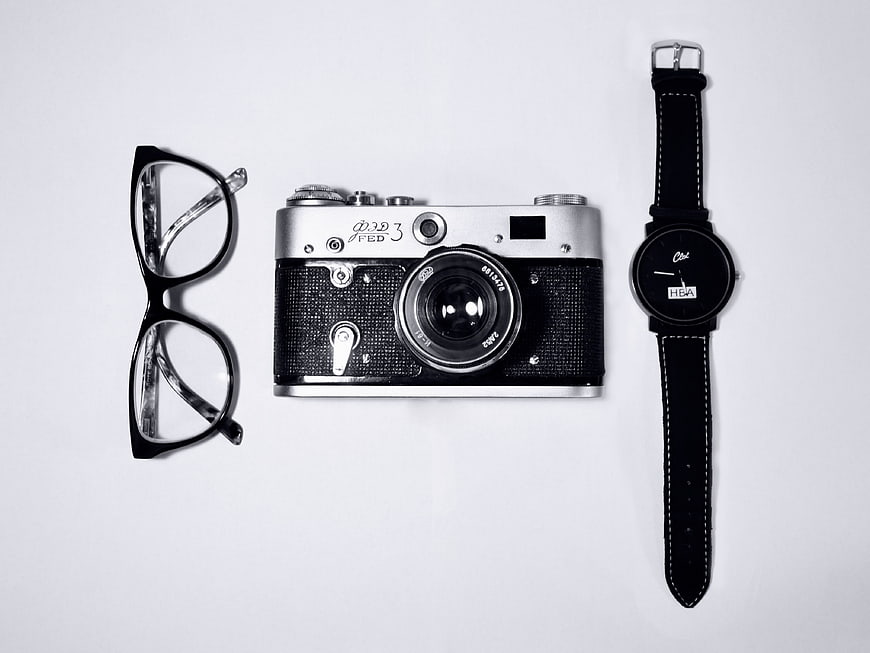 Vintage camera, glasses, and watch flat lay on white background