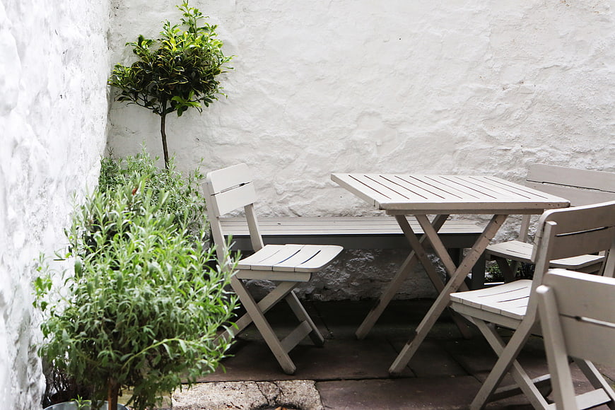 White patio furniture on a terrace with green plants