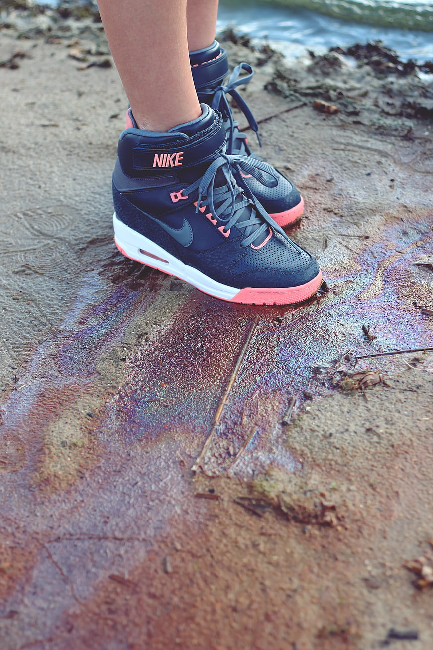 Close-up of black and pink Nike sneakers on wet sand