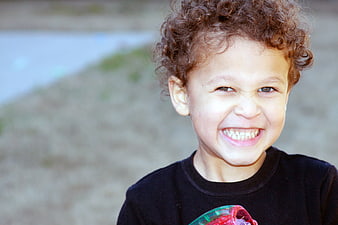 Happy Boy with Curly Hair Smiling Outdoors