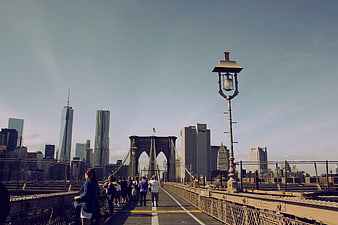 Pedestrians Walking On Brooklyn Bridge With Manhattan Skyline