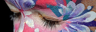 Close-up of closed eye with vibrant floral face paint and glitter
